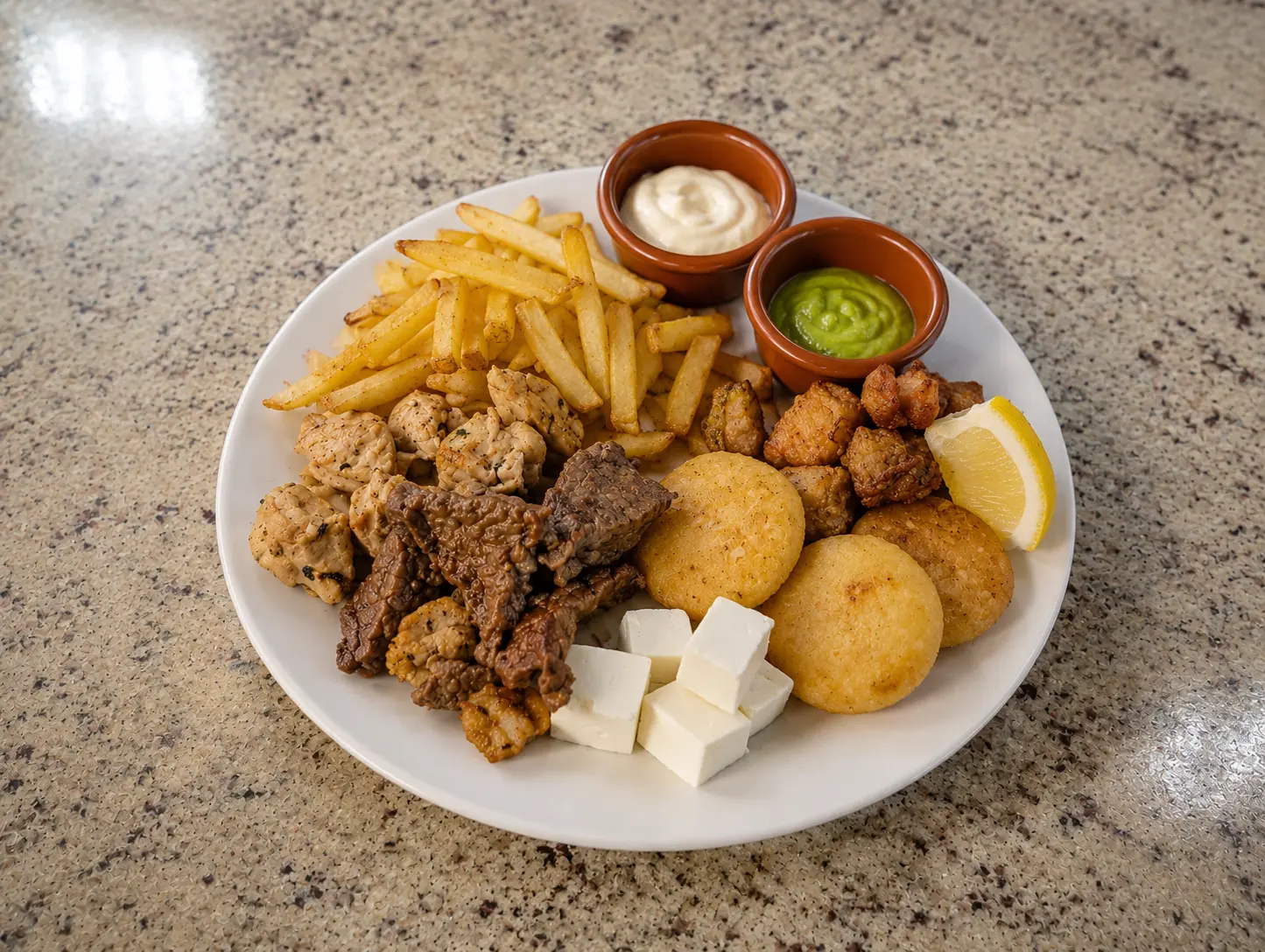 Plato de degustación con carnes, arepitas y patatas